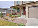 Inviting front porch with hanging plants and manicured landscaping, leading to a red front door at 890 Eva Peak Dr, Erie, CO 80516