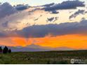 Scenic landscape featuring a vibrant sunset over rolling hills and distant mountains at 890 Eva Peak Dr, Erie, CO 80516
