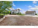 Spacious driveway leading to a well-maintained grey home and detached garage at 10481 Oxford Rd, Longmont, CO 80504