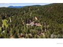 Expansive aerial shot showcasing a house nestled amongst a dense forest with a mountain range visible in the distance at 1057 Reed Ranch Rd, Boulder, CO 80302
