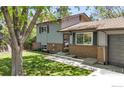 Charming two-story home featuring a well-manicured lawn, brick accents, and mature trees at 1250 Acropolis Dr, Lafayette, CO 80026