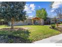 A charming home featuring a manicured lawn, a wooden porch, and large shade tree in the front yard at 1970 Willow St, Denver, CO 80220