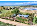 Stunning aerial view of the property showing the lush landscaping, pond and mountain views at 23111 County Road 1, Berthoud, CO 80513