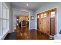 Welcoming foyer with wood floors, light walls, and a view of the modern kitchen with island at 23111 County Road 1, Berthoud, CO 80513