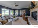 Cozy living room features large windows, a ceiling fan, and a stunning stone fireplace at 23111 County Road 1, Berthoud, CO 80513