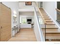 Bright foyer with wood floors, staircase with glass, and view into the open-concept living space at 2835 Links Dr, Boulder, CO 80301