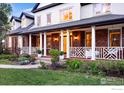 Inviting front porch featuring white columns and decorative railings, with a swing and landscaped garden at 2835 Links Dr, Boulder, CO 80301