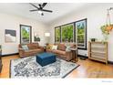 Comfortable living room featuring hardwood floors, soft brown sofas, and large windows with bright natural light at 300 E Cleveland St, Lafayette, CO 80026