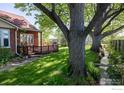 Charming backyard featuring a wooden deck, mature trees, and a small stream at 4743 Jay Rd, Boulder, CO 80301