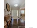 Welcoming foyer with hardwood floors, console table, and view into the home at 489 Hayloft Way, Brighton, CO 80601