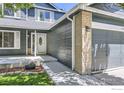 Home entrance with brick and wood accents and a well-maintained lawn at 5491 E 117Th Ave, Thornton, CO 80233