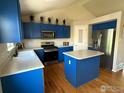Spacious kitchen with blue cabinets, stainless steel appliances, and a convenient center island at 6124 Taylor St, Frederick, CO 80530