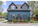 Quaint two-story blue home with cozy front porch and charming flower beds at 700 Johnson St, Louisville, CO 80027