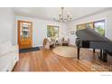 Sun-filled living room with hardwood floors, piano, and beautiful wooden door at 700 Johnson St, Louisville, CO 80027