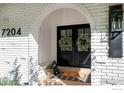 Welcoming arched entryway featuring a black double door adorned with wreaths and a stylish door mat at 7204 Rustic Trl, Boulder, CO 80301