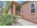 Inviting brick home featuring a cozy front porch and mature landscaping at 1012 Boxelder Cir, Longmont, CO 80503