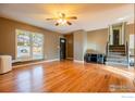 Bright living room featuring hardwood floors, ceiling fan, and staircase to upper level at 110 Lucerne Dr, Lafayette, CO 80026