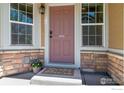 Inviting front door framed by windows, stone accents, and a welcoming entrance mat at 14300 Waterside Ln # V1, Broomfield, CO 80023