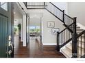 Elegant foyer with dark wood floors, staircase, and a view into the bright and airy living room at 16069 Pikes Peak Dr, Broomfield, CO 80023