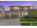 Contemporary two-story home with a three-car garage and stone accents and freshly manicured lawn at 16860 Mckay Dr, Mead, CO 80542