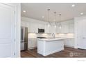 Bright kitchen features white cabinets, stainless steel appliances, a center island, and stylish pendant lighting at 197 Liberty St, Erie, CO 80516