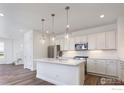 Beautiful kitchen featuring white cabinets, stainless steel appliances, large island, and wood flooring at 197 Liberty St, Erie, CO 80516