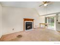 Open concept living room with a fireplace, ceiling fan, carpet, and sliding glass doors to backyard at 2167 Hackberry Cir, Longmont, CO 80501