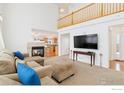 Bright living room features a fireplace, plush seating, and an open floor plan leading to the kitchen at 24285 E Wagontrail Ave, Aurora, CO 80016