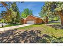 An attractive single-story brick home with a neatly maintained lawn and mature trees at 2537 Lanyon Dr, Longmont, CO 80503
