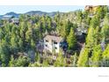 View of a charming two-story home with a deck nestled among lush trees in a natural, hilly setting at 33090 Janelle Cir, Golden, CO 80403