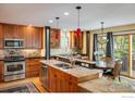 Warm kitchen featuring wood cabinets, stone countertops, stainless steel appliances, and eat-in dining area at 5523 Stonewall Pl, Boulder, CO 80303