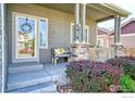 Inviting front porch with seating, stone accents and manicured landscaping leading to the entrance at 9018 Harlequin Cir, Frederick, CO 80504