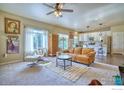 Bright and open living room with a ceiling fan, plush carpeting and a view of the kitchen at 9018 Harlequin Cir, Frederick, CO 80504