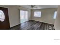 Well-lit living room featuring laminate floors, a ceiling fan, and a large sliding glass door at 9848 Lane St, Thornton, CO 80260