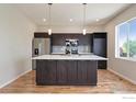 Modern kitchen with a large island, stainless steel appliances, dark cabinets and stylish backsplash at 10069 Richfield St, Commerce City, CO 80022