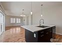 Bright open kitchen features a large island, modern pendant lighting, wood floors and stainless steel appliances at 10069 Richfield St, Commerce City, CO 80022