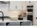 Close-up of a sleek kitchen with stainless steel appliances and white herringbone tile backsplash at 1591 Poplar Dr, Erie, CO 80516