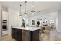 Open-concept kitchen with island, stainless steel appliances, and hardwood floors at 1591 Poplar Dr, Erie, CO 80516