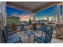 Covered front porch features stone columns and wrought iron furniture with a view of surrounding neighborhood at 1831 Ashford Cir, Longmont, CO 80504