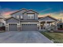 Attractive two-story home featuring a spacious three-car garage and a welcoming front porch with stone accents at 1831 Ashford Cir, Longmont, CO 80504