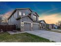 Side view of a two story home with a three car garage and stone veneer accents with an expansive concrete driveway at 1831 Ashford Cir, Longmont, CO 80504