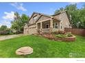 Beautifully landscaped front yard with lush green grass and mature trees around property at 1831 Ashford Cir, Longmont, CO 80504