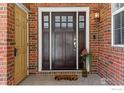 Inviting front entrance with a stylish dark wood door, brick facade, and charming details at 5017 Bella Vista Dr, Longmont, CO 80503