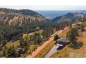 An aerial view shows a stunning home nestled in a mountainside community with treed landscape and distant mountain views at 6465 Red Hill Rd, Boulder, CO 80302