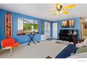Inviting living room featuring blue walls, neutral carpet, beach decor, a sleeper sofa, and a piano at 902 Pacific Pl, Fort Lupton, CO 80621