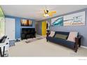 A comfortable living room with bright art, a sleeper sofa, and a stylish yellow ceiling fan at 902 Pacific Pl, Fort Lupton, CO 80621