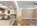 Open-concept living room with kitchen featuring a breakfast bar and wood floors at 10890 W Evans Ave # 1G, Lakewood, CO 80227