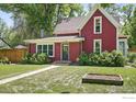 Two-story home with red siding, a green lawn, and manicured shrubs surrounding the front of the house at 1245 Longs Peak Ave, Longmont, CO 80501