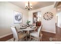 Dining room features a round table, hardwood floor, decorative painting, and a view into the kitchen at 1358 14Th Ave, Longmont, CO 80501