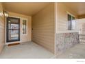 Covered front porch area with stone accents, exterior lighting, and space for outdoor seating at 1540 Murrlet St, Berthoud, CO 80513